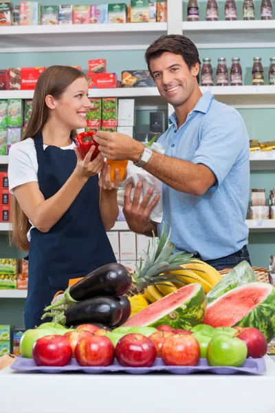 Mannelijke klant met verkoopster vergelijken van bellpepper op supermarke — Stockfoto