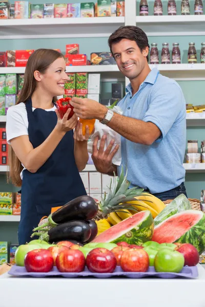 Male Customer With Saleswoman Comparing Bellpepper At Supermarke — Stock Photo, Image