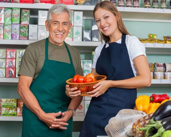 Saleswoman tenant panier de légumes avec collègue masculin en épicerie — Photo