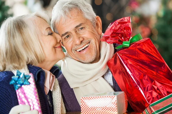 Donna in procinto di baciare l'uomo tenendo regali di Natale — Foto Stock