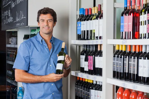 Hombre sosteniendo botella de alcohol en el supermercado —  Fotos de Stock