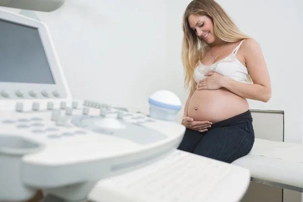 Frau hält Bauch mit Ultraschallgerät fest — Stockfoto