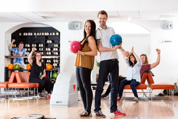 Junge Männer und Frauen mit Bowlingbällen im Club — Stockfoto