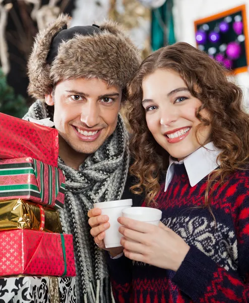 Пара с подарками и кофе в рождественском магазине — стоковое фото