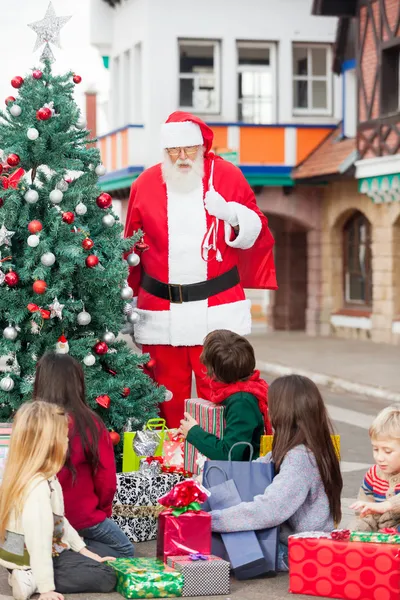 Niños con regalos mirando a Santa Claus —  Fotos de Stock