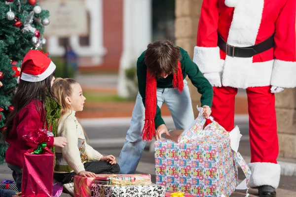 Boy Opening Christmas Present In Courtyard — Stock Photo, Image