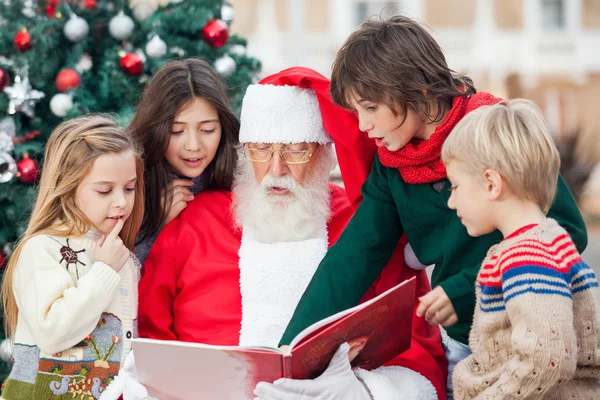 Papai Noel e crianças leitura Livro — Fotografia de Stock