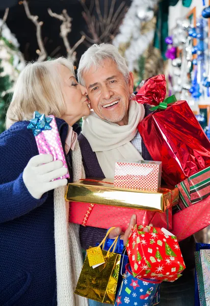 Frau küsst Mann im Weihnachtsgeschäft — Stockfoto