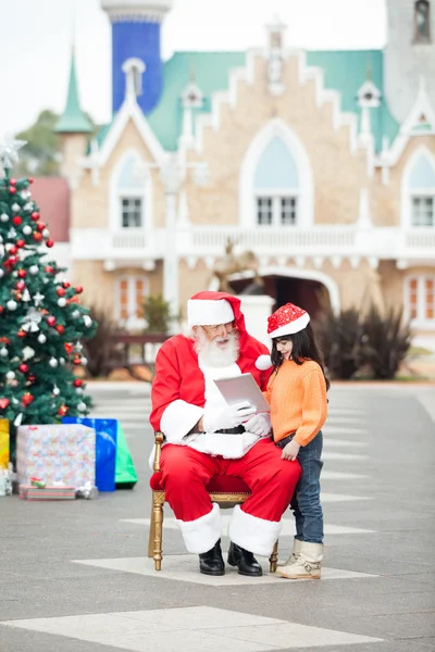 Babbo Natale mostrando tavoletta digitale alla ragazza — Foto Stock