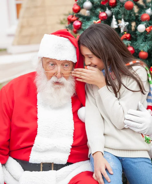 Fille chuchotant souhait dans l'oreille du père Noël — Photo