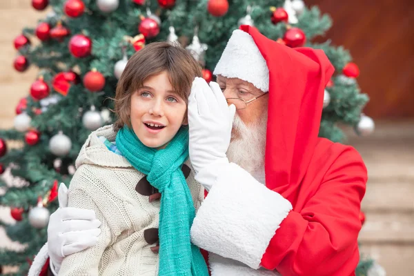 Weihnachtsmann flüstert Jungen ins Ohr — Stockfoto