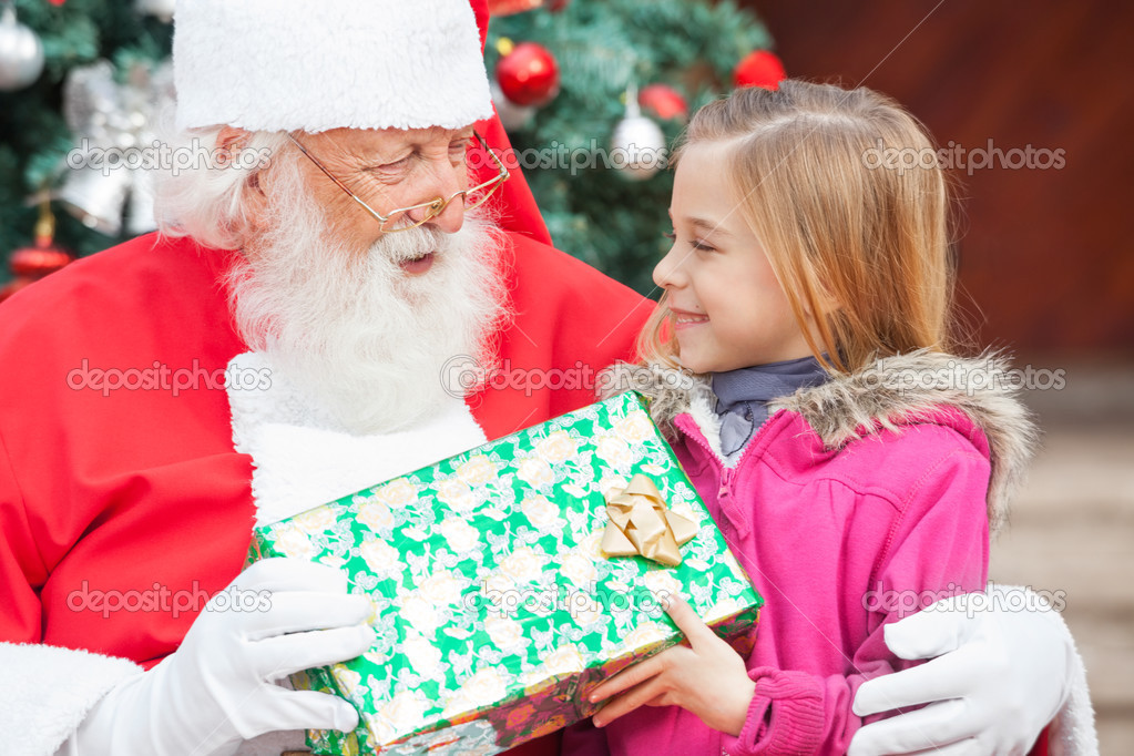 Santa Claus Giving Christmas Present To Girl