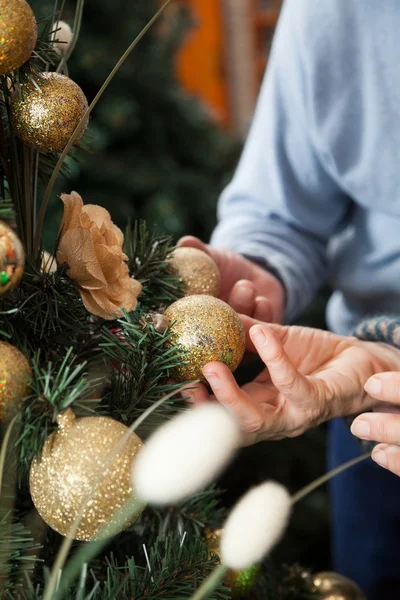 Coppia tenendo Baubles appeso sull'albero di Natale al negozio — Foto Stock