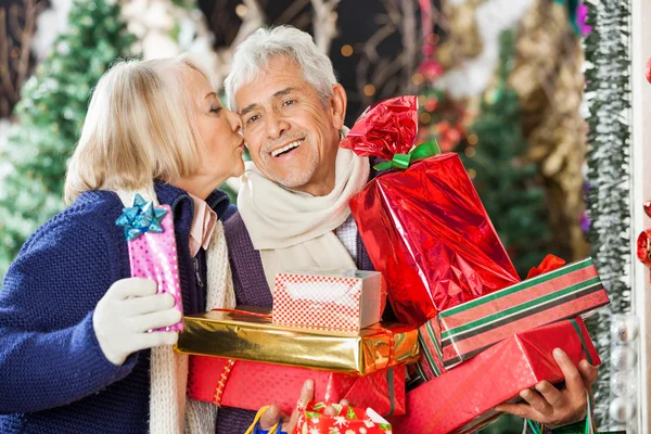 Vrouw zoenen man met Kerst presenteert — Stockfoto