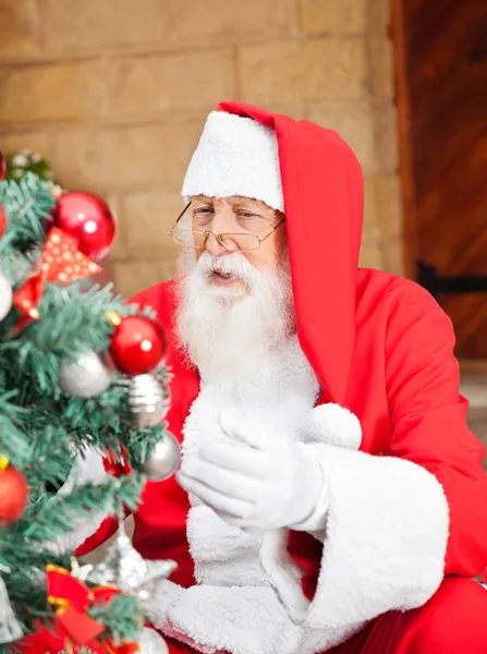 Mann als Weihnachtsmann verkleidet schmückt Weihnachtsbaum — Stockfoto