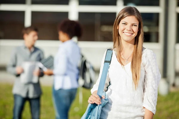 Frau trägt Umhängetasche mit Studenten im Hintergrund auf dem Campus — Stockfoto