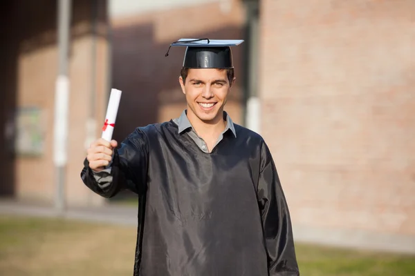 Estudante confiante mostrando diploma no dia da formatura no campus — Fotografia de Stock