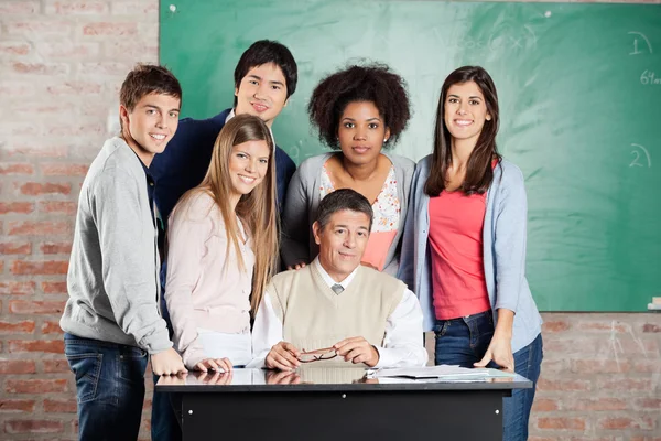 Professor e alunos na mesa contra Greenboard na sala de aula — Fotografia de Stock