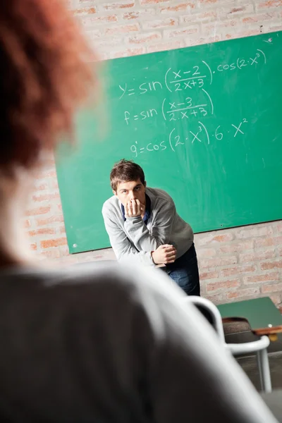 Student met hand op kin kijken naar vriend in klasgenoot — Stockfoto