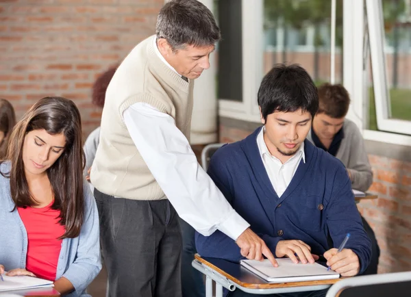 Professor Explaining Test To Student In Classroom Royalty Free Stock Photos