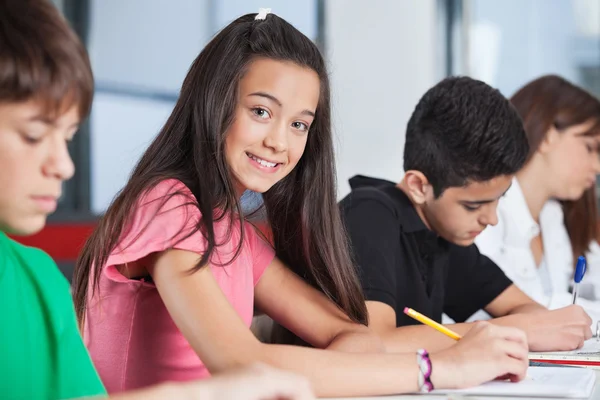 Adolescente sentada con compañeros de clase estudiando en el escritorio — Foto de Stock