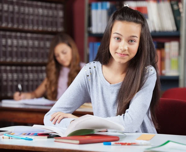 Mooie tiener schoolmeisje met boeken zit in bibliotheek — Stockfoto