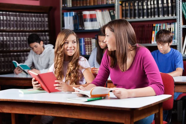 Female Friends Looking At Each Other While Sitting In Library — Stock Photo, Image