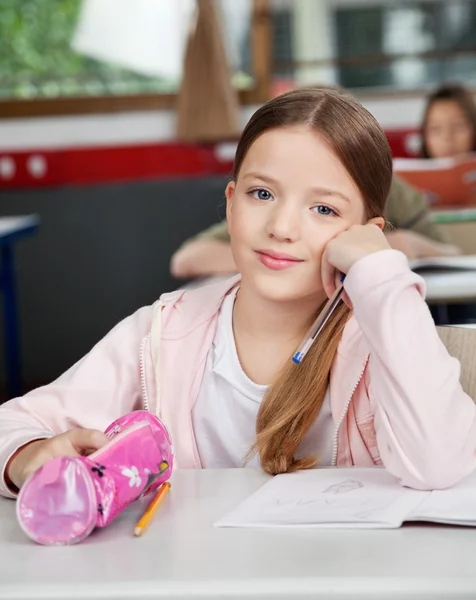 Skolflicka sitter med påse på skrivbord i klassrummet — Stockfoto