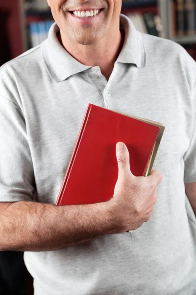 Mannelijke bibliothecaris bedrijf boek in bibliotheek — Stockfoto