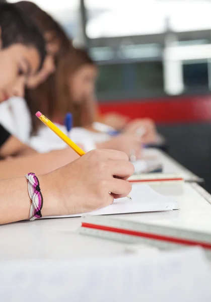 Gymnasieelever skriver på skrivbord — Stockfoto