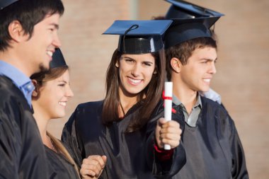 Öğrenci gösteren diploma üniversite arkadaşlarıyla dururken