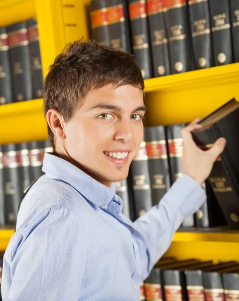 Vacker student att välja bok hylla i biblioteket — Stockfoto