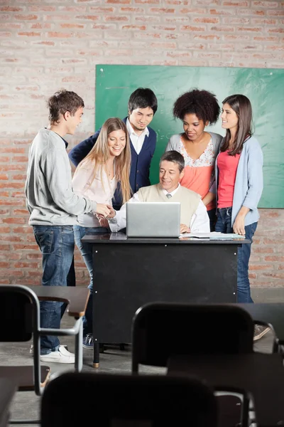 Estudiantes y profesores discutiendo sobre el ordenador portátil en el aula — Foto de Stock