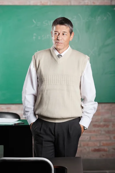 Professeur avec les mains dans les poches regardant loin dans la salle de classe — Photo