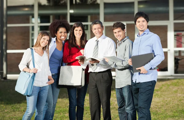 Allievi felici con insegnante in piedi sul campus universitario — Foto Stock