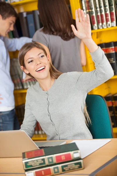 Estudiante con computadora portátil y libros saludando en la biblioteca — Foto de Stock