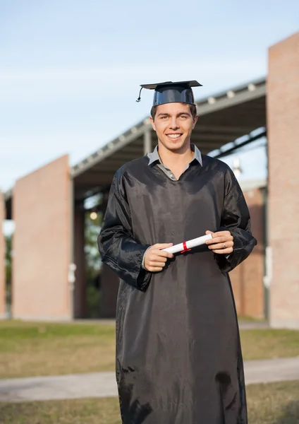 Man In Graduation Gown Holding Diploma On College Campus — Stock Photo, Image