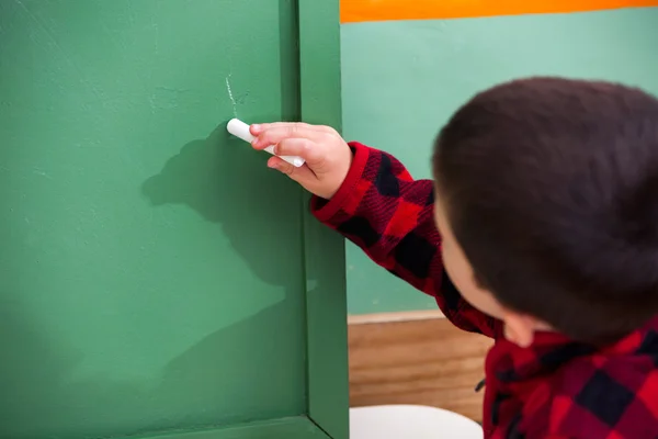 Ragazzo che scrive sulla lavagna verde all'asilo — Foto Stock