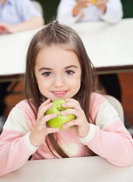 Dívka drží jablko smith se spolužáky v pozadí — Stock fotografie