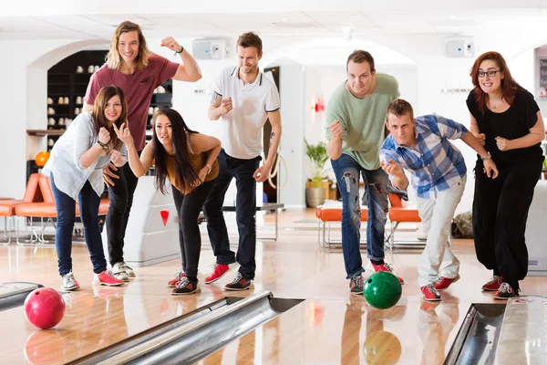 Giovani amici Bowling mentre la gente tifo — Foto Stock