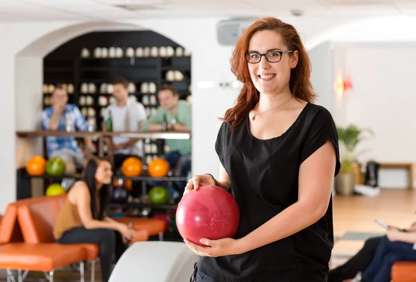 Glückliche junge Frau hält Bowlingball im Verein — Stockfoto