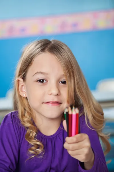 Niña sosteniendo montón de lápices de color en preescolar — Foto de Stock