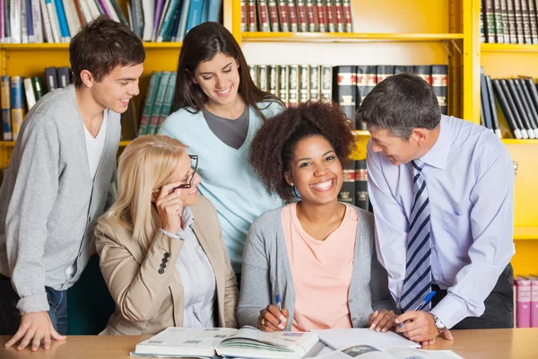 Fröhlicher Schüler mit Lehrern und Klassenkameraden in der Bibliothek — Stockfoto