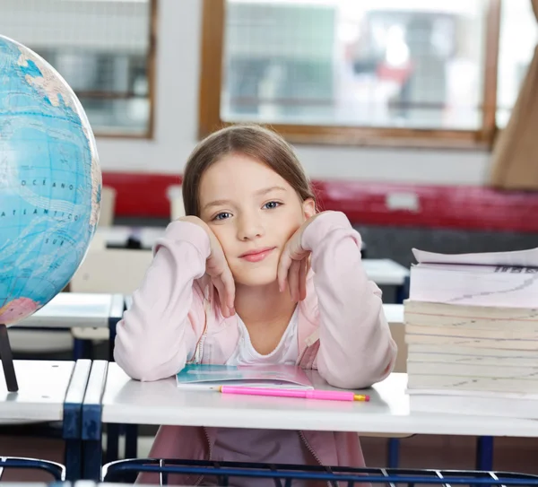 Écolière avec pile de livres et globe au bureau — Photo