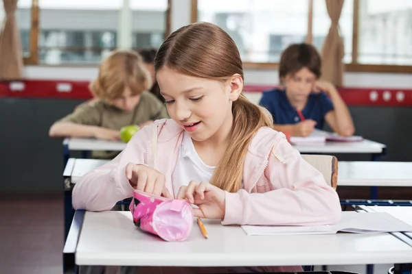 Schoolgirl Searching In Pouch At Desk — Stock Photo, Image