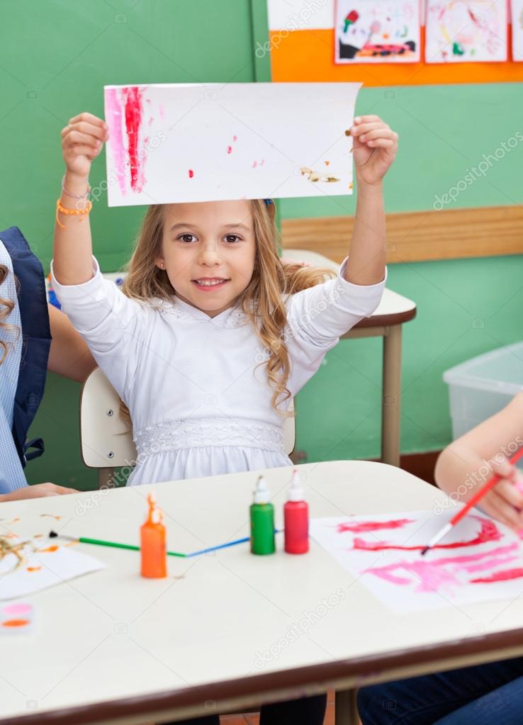 Girl Showing Painting At Classroom Desk