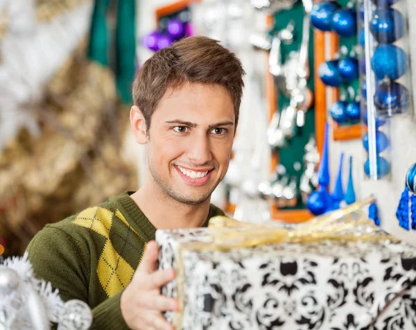 Man Holding Christmas Present In Store — Stock Photo, Image