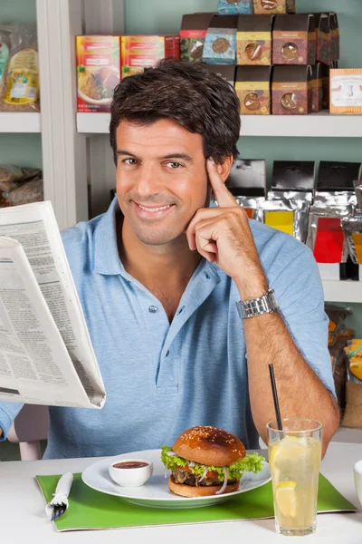 Мужской клиент с закусками и газетой в супермаркете — стоковое фото