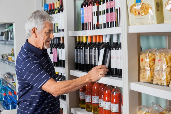 Senior wählt Wein im Supermarkt — Stockfoto