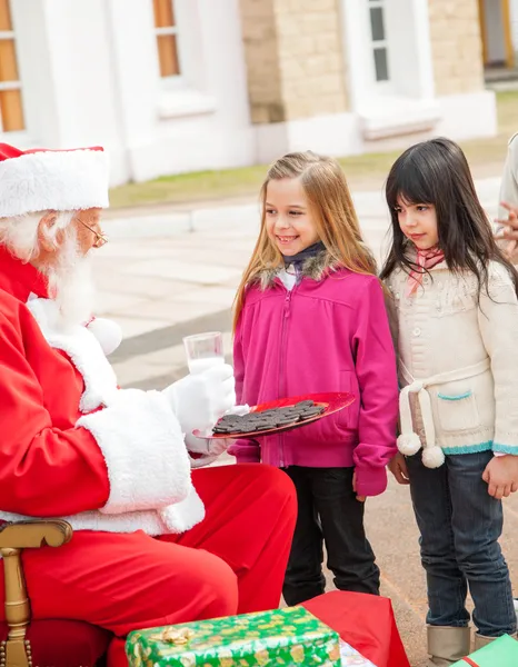 Santa Claus With Biscuits And Milk Looking At Children Stock Picture